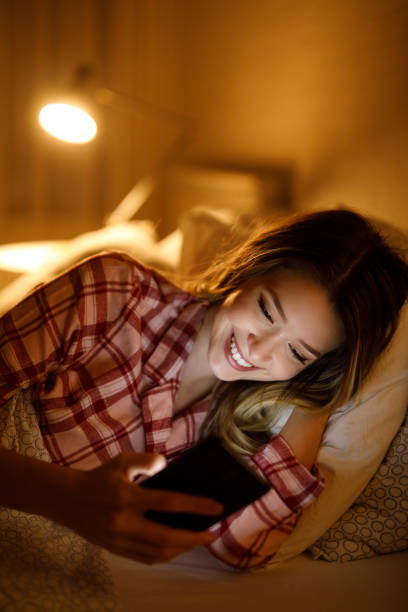 istock Beautiful young woman using mobile phone in bed at night 1223002188