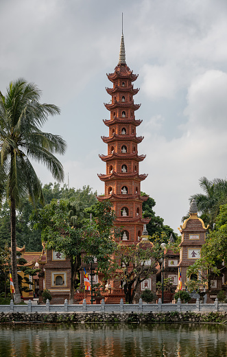 Red tower and palm in Tran Quoc temple inside West Lark in Hanoi in Northern Vietnam during cloudy day
