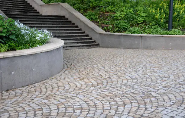 Photo of concrete retaining wall at the large staircase in the park the flowerbed area is planted with rich greenery of perennials granite paving of cubes