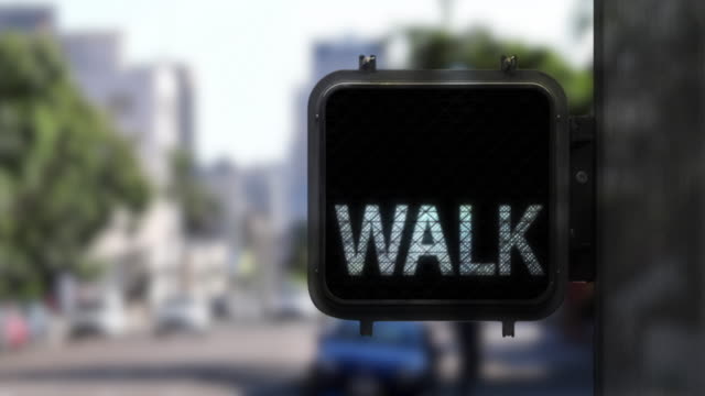 Medium shot of pedestrian crosswalk signal with white walk signal