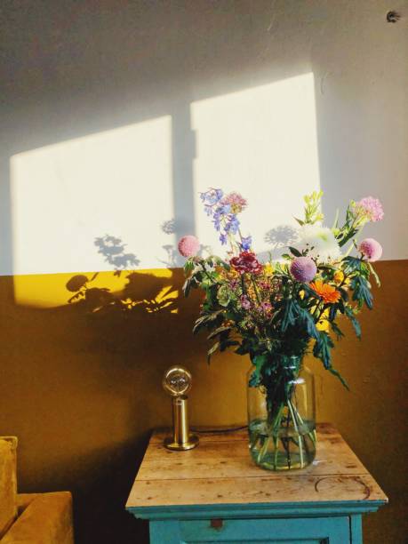 Blooming flowers in a vase in sunlight through a window