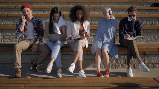 istock Multiethnic Group of Friends sitting outside, everyone is doing 1223012982