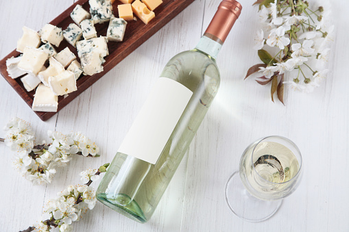 Bottle of wine, cheese and flowers on a wooden background top view