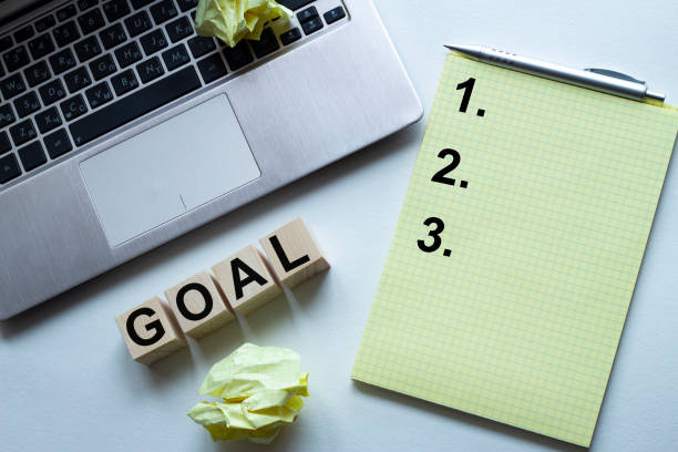 istock Small notebook with 2019 goals text is on top of white office desk table with laptop computer and supplies. Top view, flat lay. New year resolutions concept. 1223020570