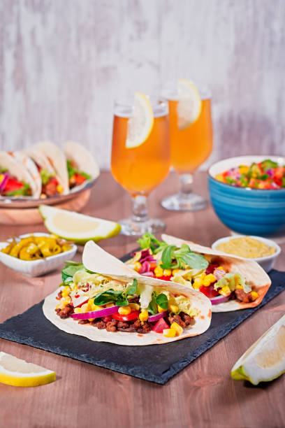istock Table with tacos, mango salsa, nachos with sauce, guacamole, lemon beer for Cinco de Mayo celebration party. Appetizers and traditional mexican dishes for family dinner on wooden table top, copy space 1223022276