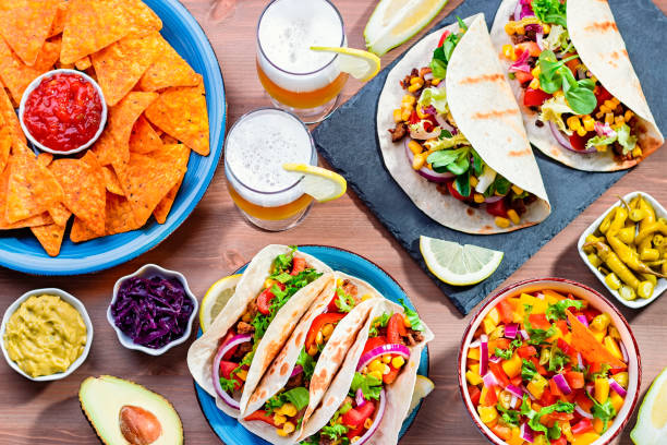 istock Table with tacos, mango salsa, nachos with sauce, guacamole, lemon beer for Cinco de Mayo celebration party. Appetizers and traditional mexican dishes for family dinner on wooden table top, copy space 1223022283