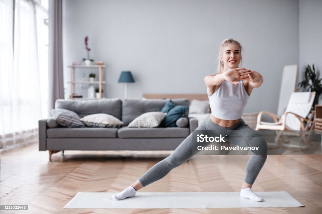 Sporty young woman doing exercise alone in living room. Sporty young woman doing exercise alone in living room. Workout at home. Home Workout Stock Photo