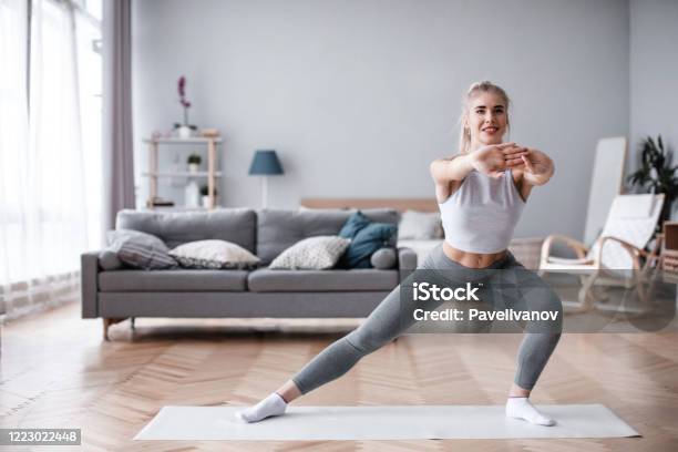 Sporty Young Woman Doing Exercise Alone In Living Room Stock Photo - Download Image Now