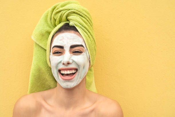 happy girl applying facial mask portrait - young woman having skin care spa day - beauty clean treatment day and cosmetology products concept - face mask imagens e fotografias de stock