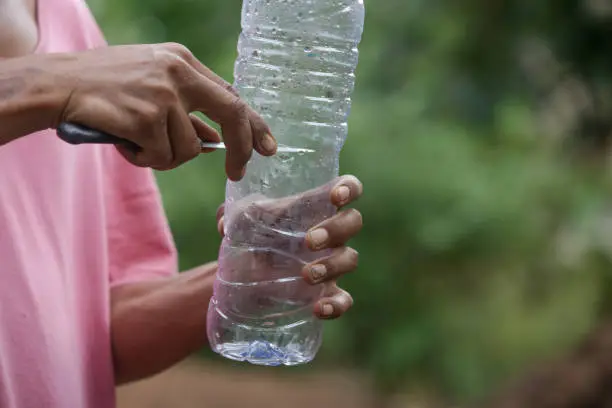 Photo of Process of making a self-watering pot for plants out of a waste plastic. Single use plastic bottle recycling idea. Zero waste sustainable lifestyle concept.