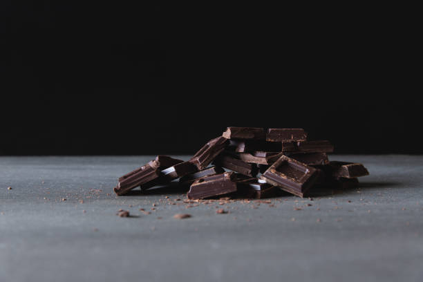 istock Dark chocolate pieces, broken, chopped stack of black chocolate, Dark background 1223025833