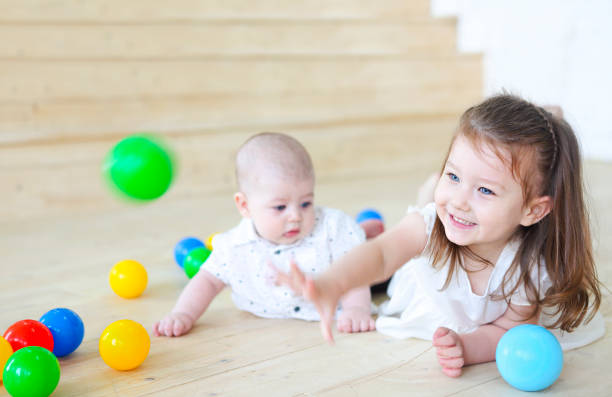 男の子と彼の妹はボールで遊んでいます。子供のためのカラフルなおもちゃ。プレイルームの子供たち - playground cute baby blue ストックフォトと画像
