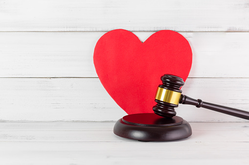 Judge Gavel Hammer with Red Heart on white wood background. Family or Love of Law Concept with Copy Space.