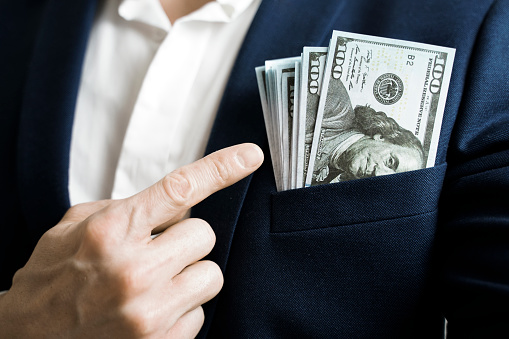 Money success concept. 100 dollar bills in businessman jacket pocket. Symbol of success and wealth.