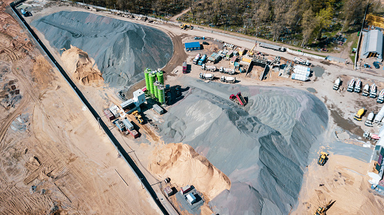 Aerial view of concrete and cement mortar plant. Concrete mixing silo for stone and sand. Bulk material storage site. Industrial concept and construction background.