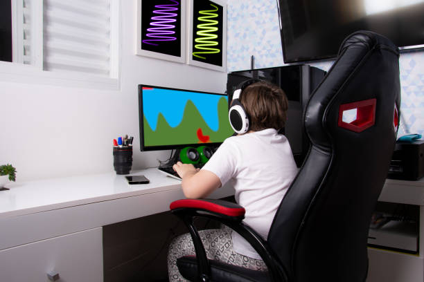 boy sitting on gamer chair playing on computer boy sitting on gamer chair playing on computer gaming chair photos stock pictures, royalty-free photos & images