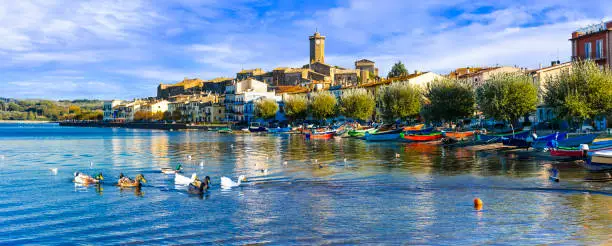 Photo of beautiful lake Lago di Bolsena and scenic medieval village Marta. Italy