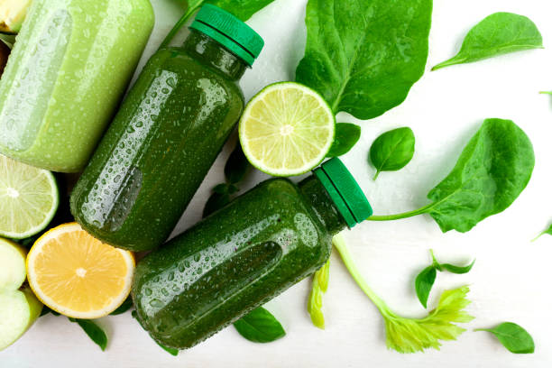 istock A creative composition of few bottles filled with various green beverages on a white background in amongst of stems of fresh plants, various fruits and vegetables: apple, limes 1223036773