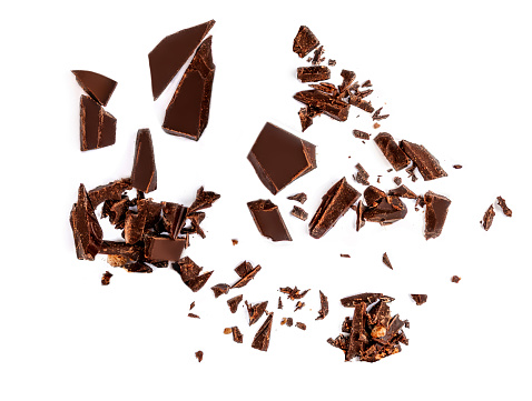 Caída de piezas de chocolate y virutas aisladas sobre fondo blanco