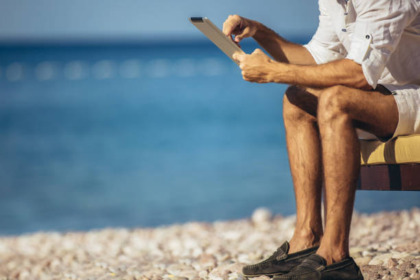 istock Man relaxing and use tablet computer at sea beach 1223038053