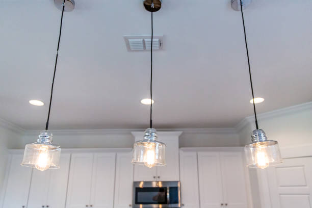 istock Three hanging pendant lights in a modern new construction white cabinet kitchen and a vent in the ceiling 1223041462