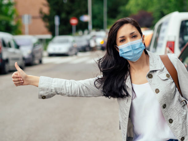 istock Woman hitchhiking. She's wearing a protective mask. 1223042296