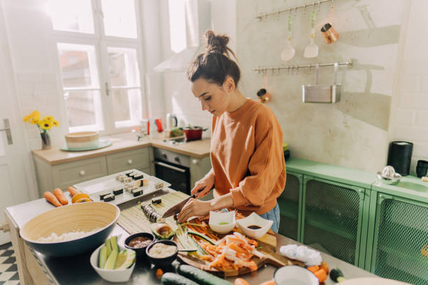 istock Young woman cutting sushi rolls 1223043648