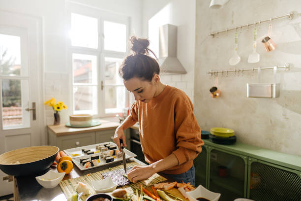 istock Young woman making avocado sushi rolls 1223044111