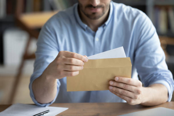 istock Focused businessman reading letter, holding envelope in hands close up 1223044285