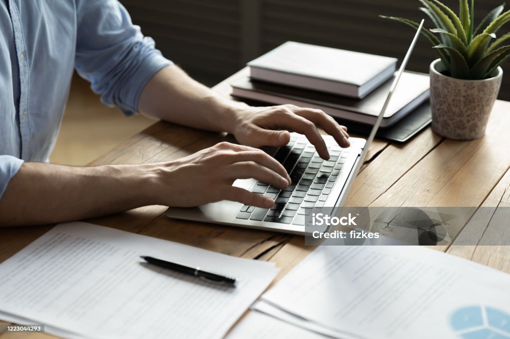 Close up businessman using laptop, sitting at work desk Close up businessman using laptop, typing on keyboard, sitting at wooden desk with documents, writing email, accountant writing financial report, busy student studying online, searching information Writing - Activity Stock Photo