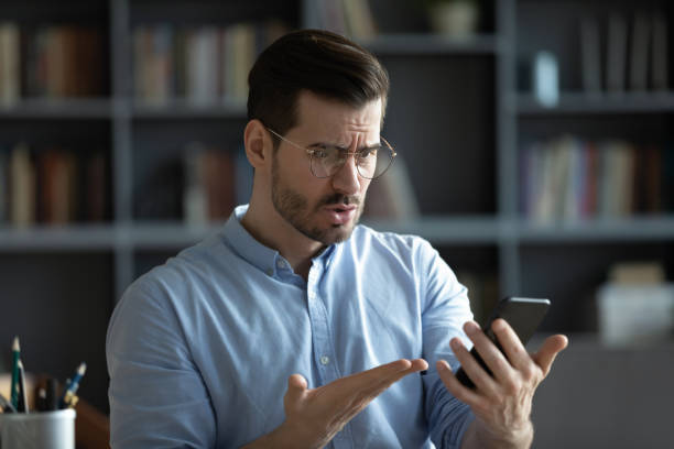 istock Unhappy irritated man wearing glasses having problem with smartphone 1223044299