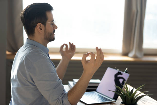 Calm peaceful businessman meditating, sitting at work desk