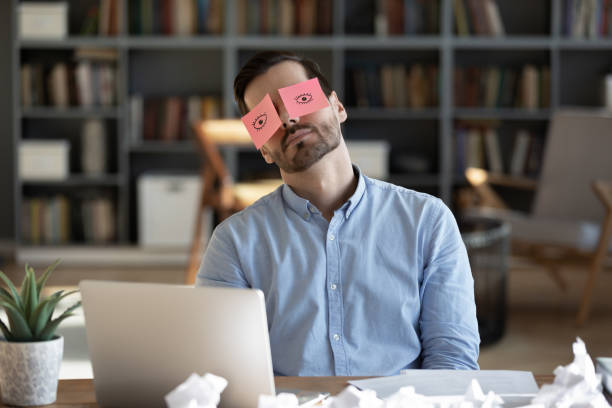 измученный уставший бизнесмен с наклейками на глазах спит на рабочем месте - creativity inspiration humor business стоковые фото и изображения