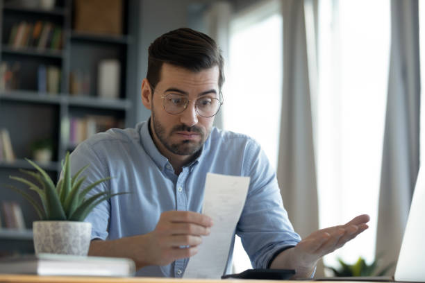 istock Confused shocked man looking at receipt, checking bills 1223044345