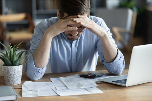 Triste hombre deprimido revisando facturas, ansiedad por la deuda o la bancarrota photo