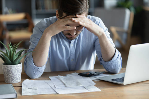 Sad depressed man checking bills, anxiety about debt or bankruptcy Sad depressed man checking bills, anxiety about debt or bankruptcy, financial problem, bank debt or lack of money, unhappy frustrated young male sitting at work desk with laptop and calculator bust stock pictures, royalty-free photos & images