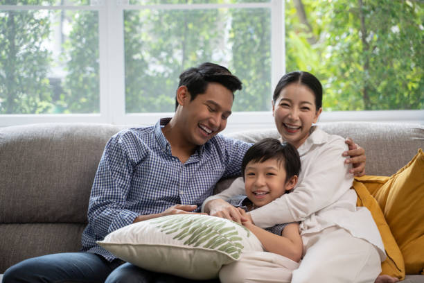 portrait of happy Asian family spending time together on sofa in living room. family and home concept. portrait of happy Asian family spending time together on sofa in living room. family and home concept. family asian ethnicity couple child stock pictures, royalty-free photos & images