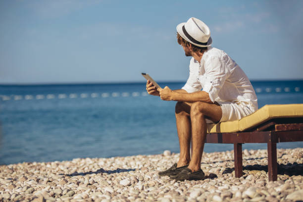 istock Man relaxing and use tablet computer at sea beach 1223047593