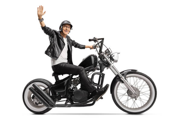 istock Elderly biker in leather jacket riding a chopper and waving 1223049179