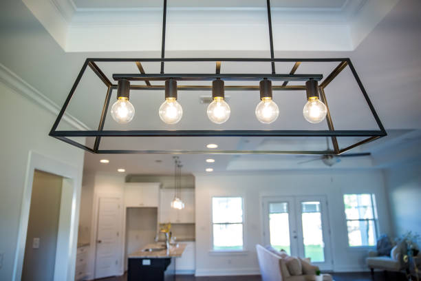 Hanging retro black metal iron chandelier lighting fixture hanging in a dining room of a new construction house Hanging retro black metal iron chandelier lighting fixture with vintage bulbs hanging in a dining room of a new construction house light fixture stock pictures, royalty-free photos & images