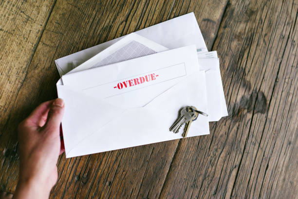 achterstallige notiice in een open envelop met sleutels op een houten tafel - handen van een vrouw holding - late bills - huur - hypotheek - rental stockfoto's en -beelden
