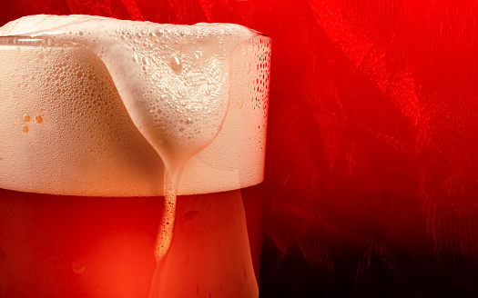 Glass of craft beer on red background. The concept of food.