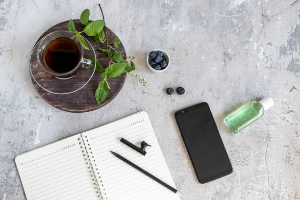istock Cozy work at home. Black coffee, notebook, green leaves, antiseptic, blueberry on a concrete table. 1223053283