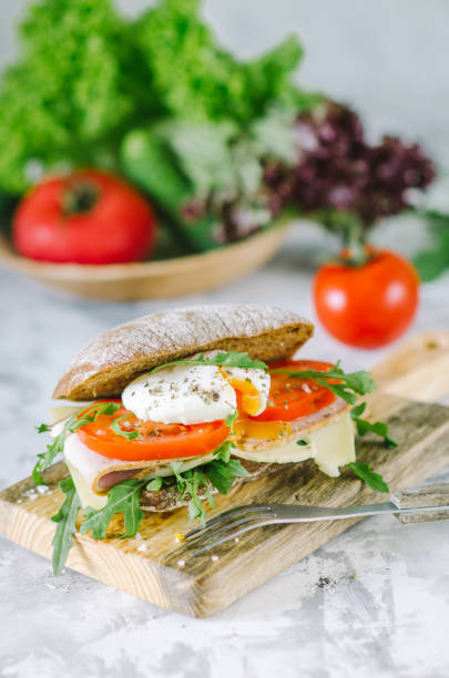 istock Delicious ciabatta sandwich with ham, tomatoes, arugula and egg poached. 1223053383