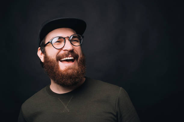 Close up photo of a bearded man with a large smile on black background. stock photo