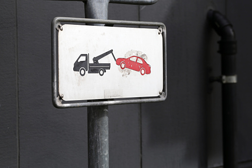 Sign telling it's prohibited to park your car here, or if you do it will be towed away in downtown Zürich, Switzerland, March 2020. In the sign you can see a breakdown lorry / tow car towing a car.