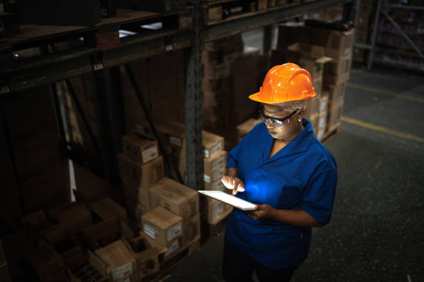 Female worker walking and using digital tablet in warehouse Female worker walking and using digital tablet in warehouse working overtime stock pictures, royalty-free photos & images
