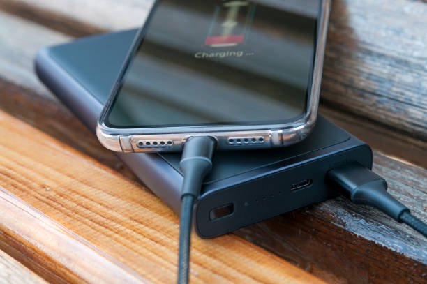 istock Modern smartphone charges from the power bank on the wooden background. Modern technology. Selective focus. 1223055368