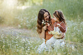Happy mother and little girl picking flowers