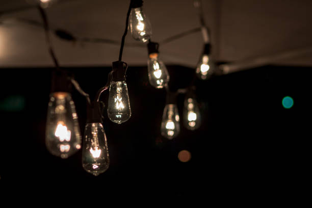 String of lightbulbs hanging from a tent at night stock photo